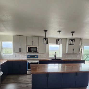 modern kitchen with navy blue lower cabinets, wood countertops, and large island